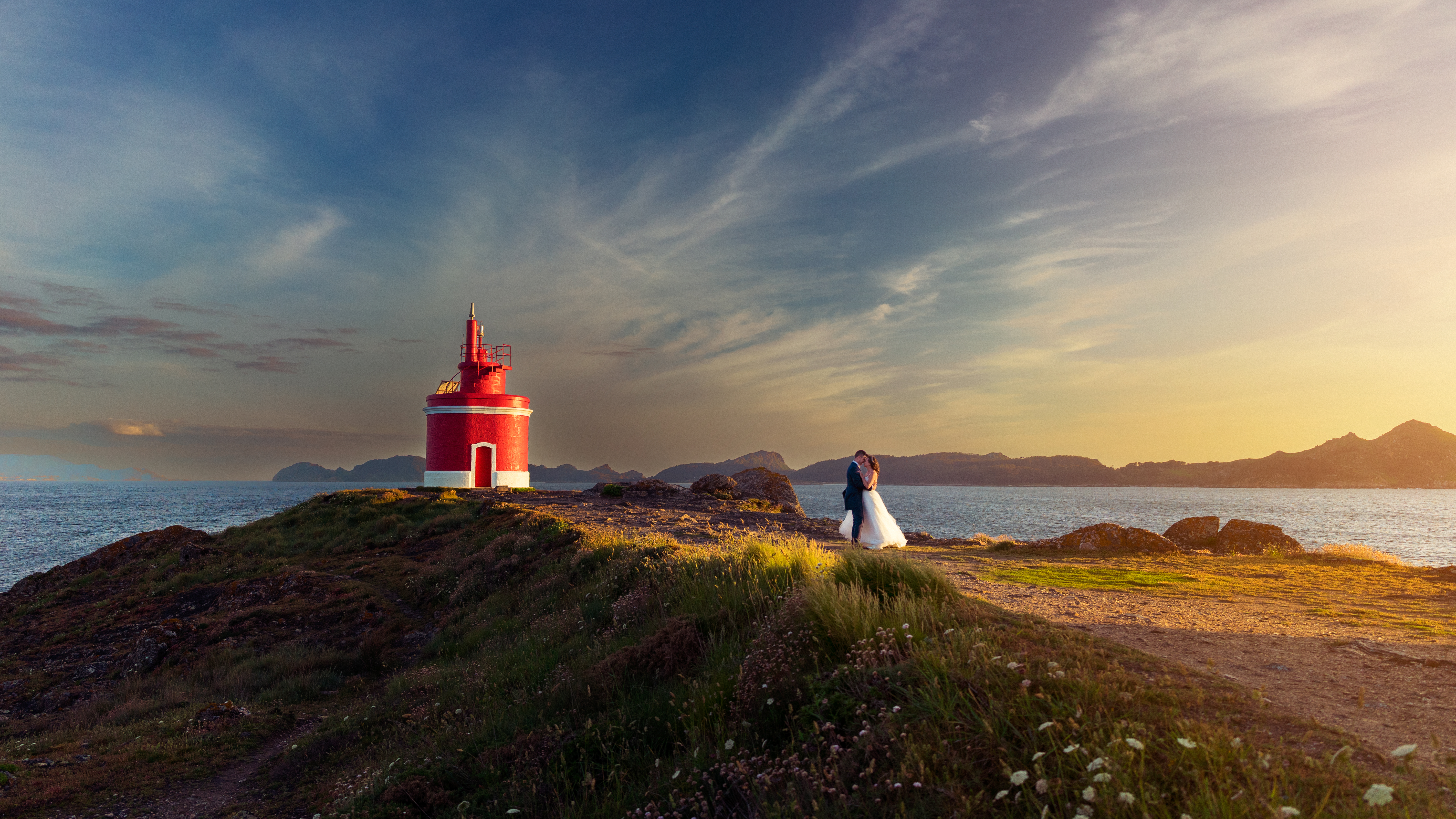 Couple by a red lighthouse in Iceland at sunset